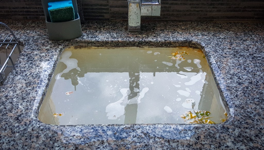 Overflowing kitchen sink, clogged drain. Plumbing problems.